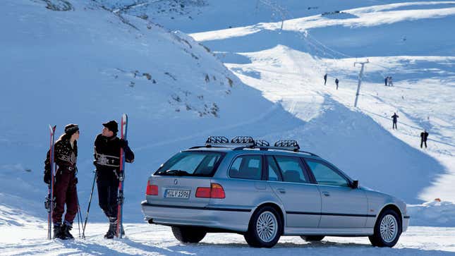 A photo of a BMW 3 Series wagon parked in the snow. 