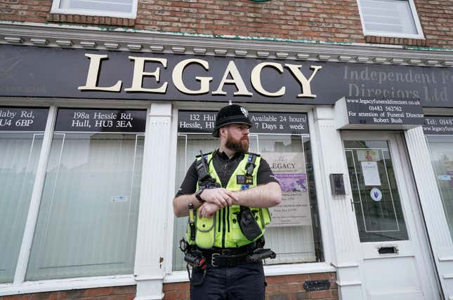 Police stand guard outside the Beckside branch of Legacy Independent Funeral Directors, in Hull, England, Saturday, March 9, 2024. Police in northern England say they have removed 34 bodies from a funeral home and arrested a man and woman on suspicion of fraud and preventing lawful burials. The arrests Sunday follow several days of investigation at Legacy Funeral Directors in Hull and two related funeral homes. (Danny Lawson/PA via AP)