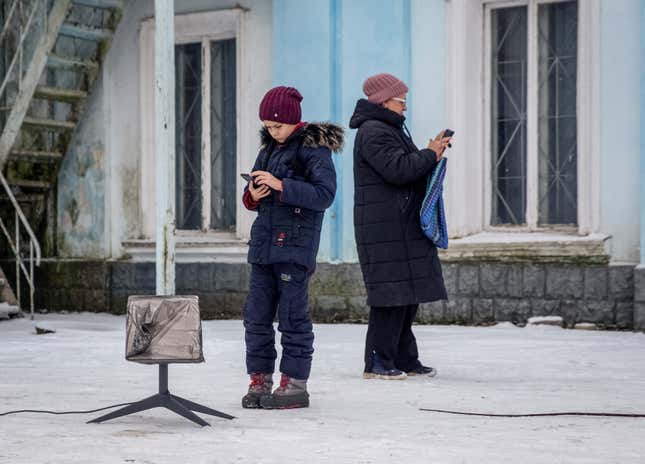 Local residents of Chasiv Yar, Donetsk region, Ukraine stand in the snow and use a Starlink terminal