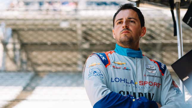 Stefan Wilson, dressed in his firesuit, stands in the pits of the Indianapolis Motor Speedway during practice for the 2022 Indy 500. 