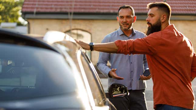 Salesperson showing a car to a customer