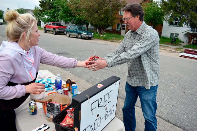 Chandler Peabody, left, gives a free meal to Perry Roberts near a  flood-damaged neighborhood in Red Lodge, Mont., Tuesday, June 14, 2022.  Roberts’ basement was inundated, ruining his hot water heater and  furnace. 