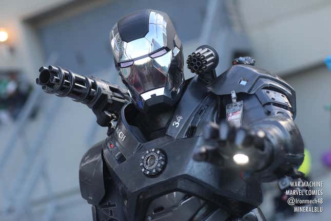 A cosplayer dressed as War Machine readies their hand cannons. 