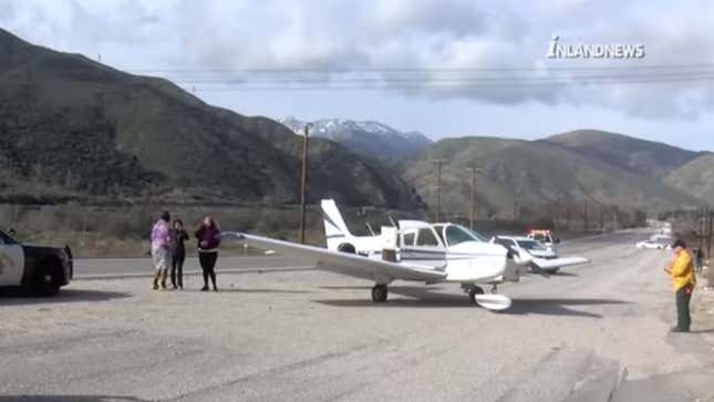 A photo of a small plane landed by the side of the road. 