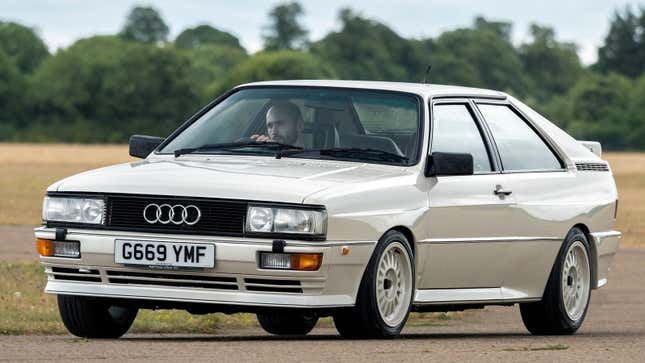 A white 1988 Audi Quattro driving on a track 