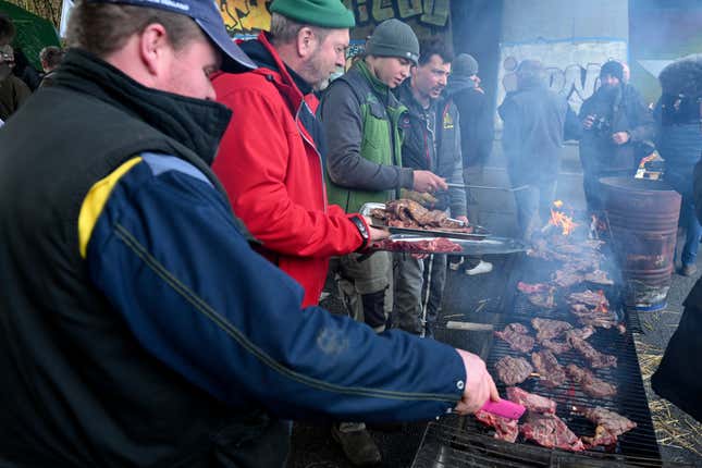 Farmers attend a barbecue as they occupy a speedway, Thursday, Jan. 25, 2024 near Valdampierre, north of Paris. Snowballing protests by French farmers crept closer to Paris on Thursday, with tractors driving in convoys and blocking roads in many regions of the country to ratchet up pressure for government measures to protect the influential agricultural sector from foreign competition, red tape, rising costs and poverty-levels of pay for the worst-off producers. (AP Photo/Matthieu Mirville)