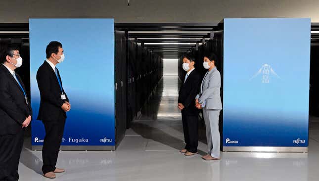 four people wearing white face masks standing in front of two rows of servers