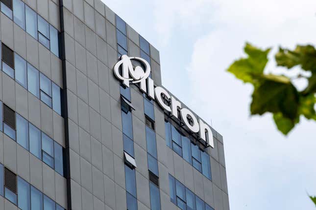 Micron sign on office building, some tree leaves are blurred in the upper right corner