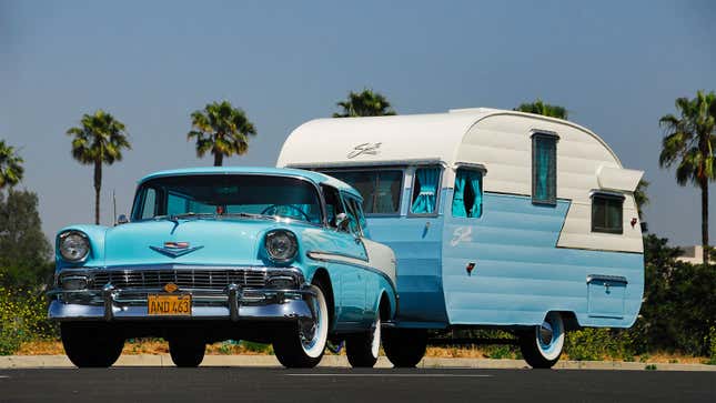 A photo of a pale blue Chevrolet Bel Air towing a matching caravan. 