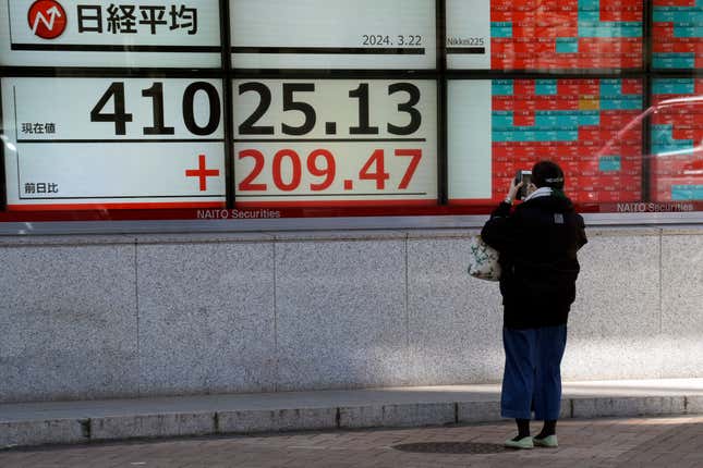 A person takes a photo of an electronic stock board showing Japan&#39;s Nikkei 225 index at a securities firm Friday, March 22, 2024, in Tokyo. Stocks were mostly lower Friday in Asia after Wall Street tapped fresh records, led by big gains in chipmakers. (AP Photo/Eugene Hoshiko)