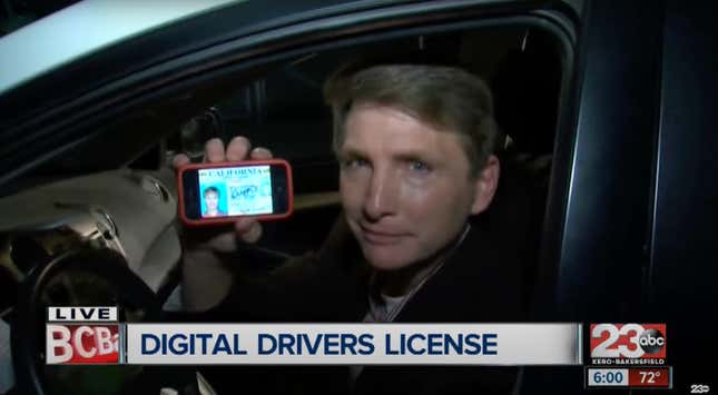 A man holds up his cell phone with a driver's license on the screen