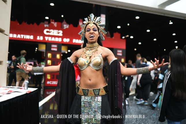 A cosplayer dressed as Akasha stands with her arms outstretched. 