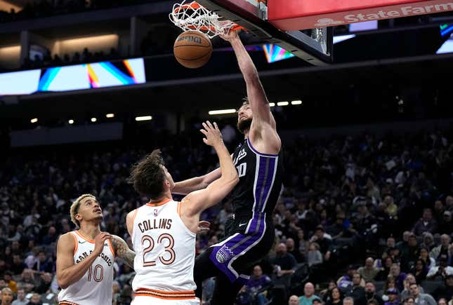 SACRAMENTO, CALIFORNIA - FEBRUARY 22: Domantas Sabonis #10 of the Sacramento Kings slam dunks over Zach Collins #23 of the San Antonio Spurs in the fourth quarter at Golden 1 Center on February 22, 2024 in Sacramento, California. NOTE TO USER: User expressly acknowledges and agrees that, by downloading and or using this photograph, User is consenting to the terms and conditions of the Getty Images License Agreement. (Photo by Thearon W. Henderson/Getty Images)