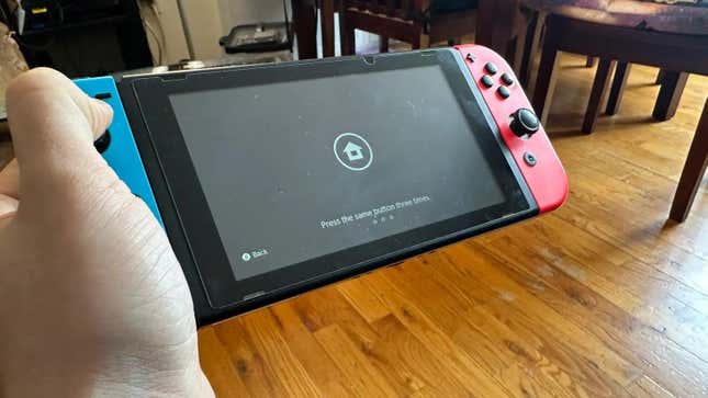 Konsol Nintendo Switch di tangan menampilkan layar login utama.