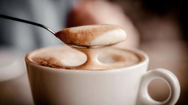 咖啡拿铁牛奶从杯子中勺出