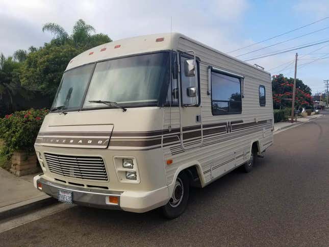 A beige and brown 1986 Winnebago Chieftan motorhome is parked on a street.