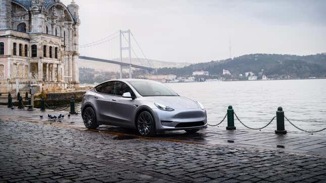 A silver Model Y Parked on cobblestones near a body of water