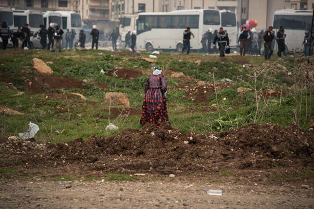 A woman watches police run away from clouds of tear gas after a brief clash between security forces and attendees at the end of the Newroz celebration.