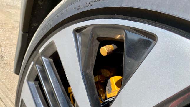 A close-up of my press car's dirty wheels and the gold tire valve stem caps and brake calipers