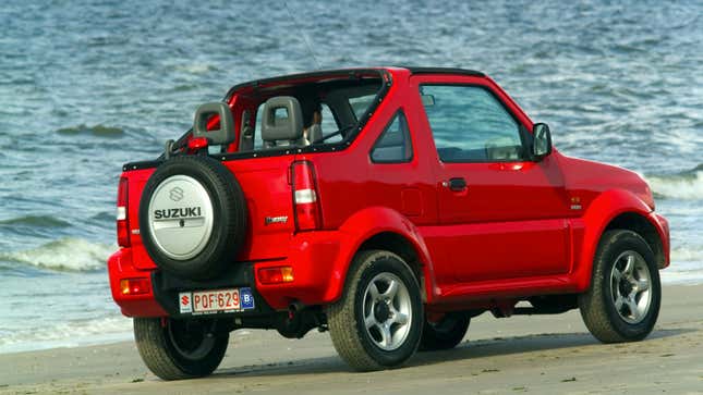 A red Suzuki Jimny parked by a beach 