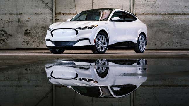 A photo of a white Ford Mustang Mach-E SUV with a reflection of it on some water. 