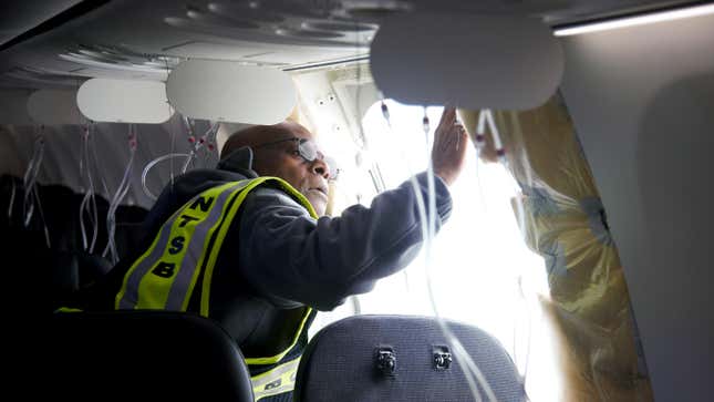 An investigator examines the door plug area of Alaska Airlines flight that suffered the door plug blowout