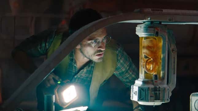 A man looks at a dino fetus in a container.