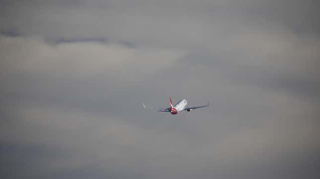 A Qantas airways plane flying into a cloudy sky 