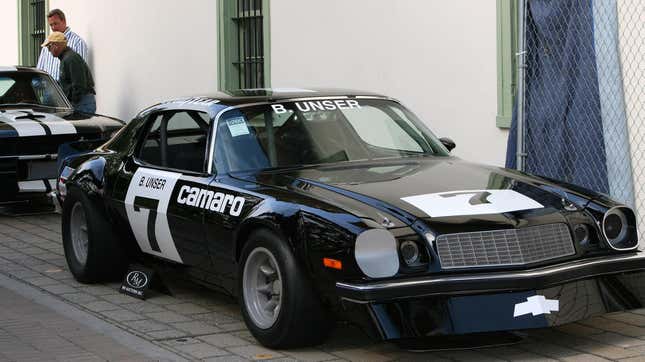 Un Chevrolet Camaro de carreras negro estacionado frente a un edificio