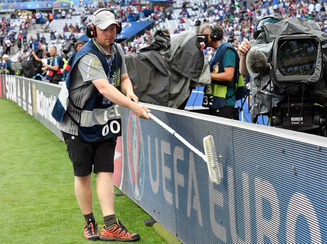 A man tries to sweep away moths on an advertising board before the Euro 2016 final soccer match between Portugal and France at the Stade de France in Saint-Denis, north of Paris, Sunday, July 10, 2016. (AP Photo/Martin Meissner)