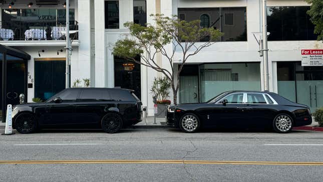 Side view of a black Range Rover parked in front of a black Rolls-Royce Phantom