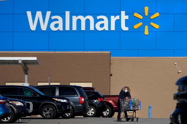 FILE - In this Nov. 18, 2020 file photo, a woman wheels a cart with her purchases out of a Walmart store, in Derry, N.H. The holiday season is here, which means spending time with family on Thanksgiving and hunting for the best deals on Black Friday. The term “Black Friday” was linked to a financial crash in the late 1800s and became associated with shopping the day after Thanksgiving in the mid-1900s. A number of stores will be closed on Thanksgiving, including Walmart and Target. (AP Photo/Charles Krupa, File)