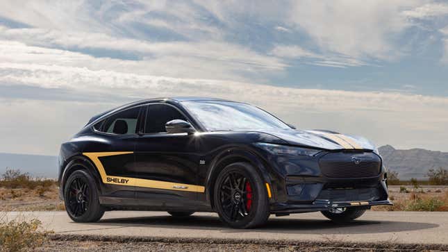 A front 3/4 view of a Shelby Hertz Mustang Mach-E parked in the desert showing off its black paint and gold accents