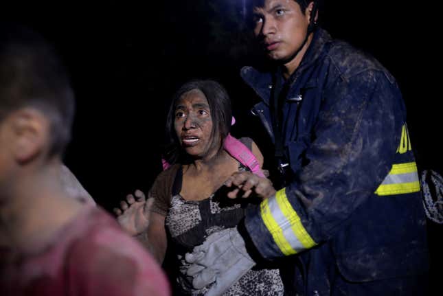 A rescue worker helps a woman covered with ash after Fuego volcano erupted violently in El Rodeo, Guatemala June 3, 2018. REUTERS/Fabricio Alonzo - RC1936B8FE70