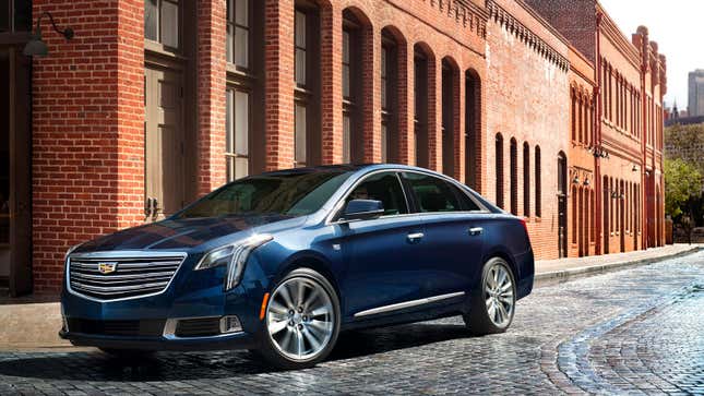 A photo of a blue Cadillac XTS sedan on a cobble street. 