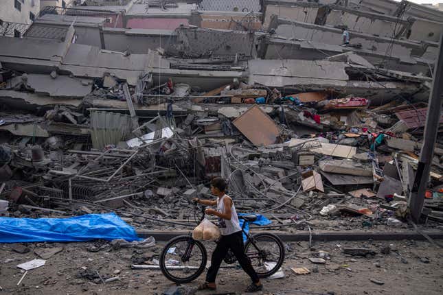 FILE - A Palestinian child walks with a bicycle by the rubble of a building after it was hit by an Israeli airstrike, in Gaza City, Sunday, Oct. 8, 2023. A new U.N. report paints a stark picture of the devastating collapsing Palestinian economy after a month of war and Israel’s near total siege of Gaza. (AP Photo/Fatima Shbair, File)