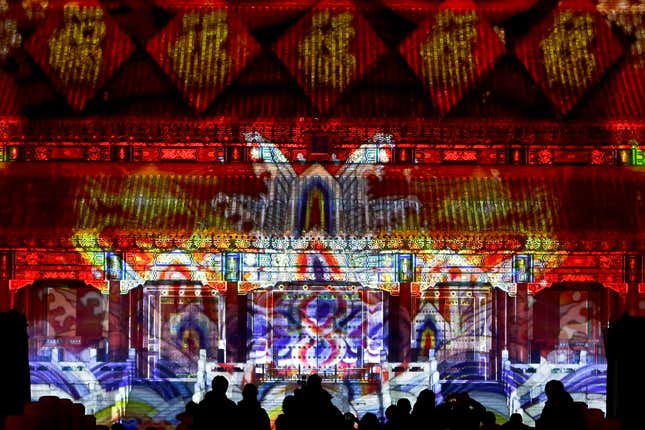Visitors watch the Forbidden City is illuminated with colorful lights during the Lantern Festival in Beijing, Tuesday, Feb. 19, 2019. Beijing's Palace Museum was illuminated and opened for night visits to celebrate China's Lantern Festival. For the first time since it was established 94 years ago, the Palace Museum, also known as the Forbidden City, extended opening hours till nighttime and lit up part of its cultural relics buildings. (AP Photo/Andy Wong)
