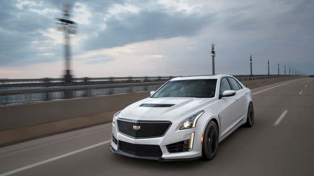 A photo of a white Cadillac sedan driving down a highway. 