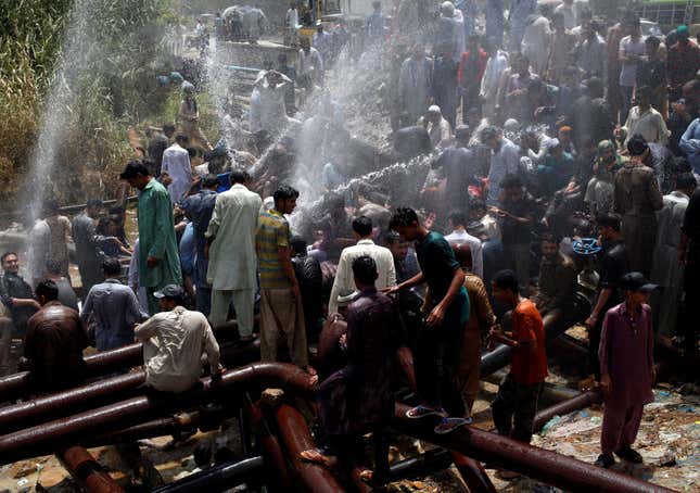 Residents cluster around the spray from a leaking water pipeline in Karachi.