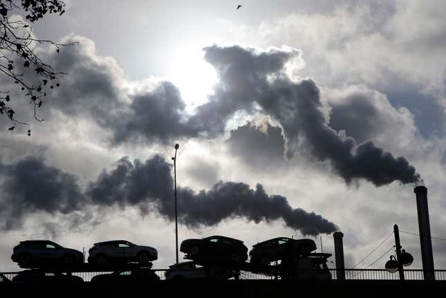 FILE - Smoke rises from a factory as a truck loaded with cars crosses a bridge in Paris, on Nov. 30, 2018. President Emmanuel Macron is to unveil France&#39;s approach and means to meet its climate-related commitments within the next seven years as a special government meeting is taking place on Monday Sept. 25, 2023. (AP Photo/Michel Euler, File)