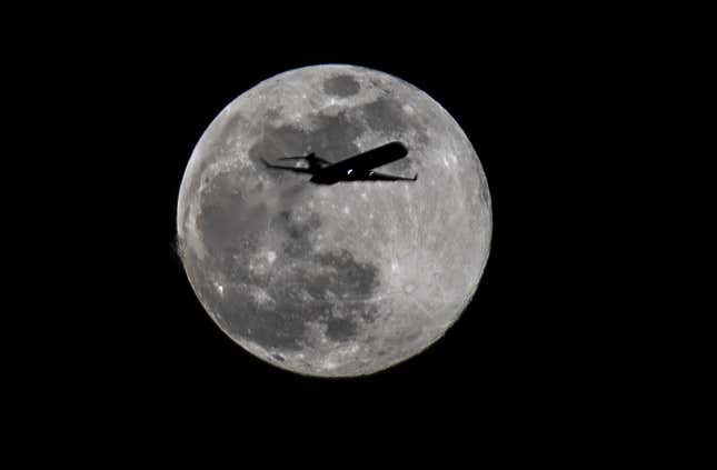 A plane passes in front of the moon on the first day of spring in Frankfurt am Main, Germany.