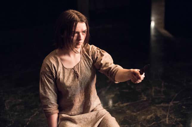 Arya holds a knife in her hand and looks resolved to stab someone with it.