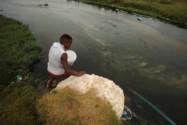 A man fills up a containers with water from a polluted river near Cape Town as the city’s water crisis mounts on Feb. 2, 2018.