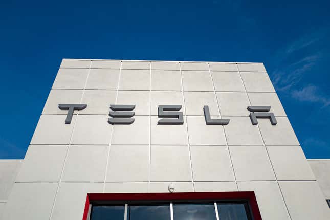 Low-angle view of facade of Tesla dealership with logo and sign