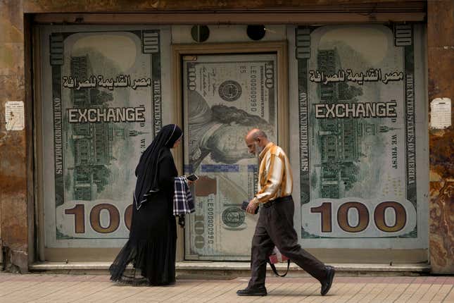 Egyptians walk past an exchange office in Cairo, Egypt, Wednesday, March 6, 2024. The Egyptian pound slipped sharply against the dollar on Wednesday after the Central Bank of Egypt raised its main interest rate and said it would allow the currency&#39;s exchange rate to be set by market forces. (AP Photo/Amr Nabil)