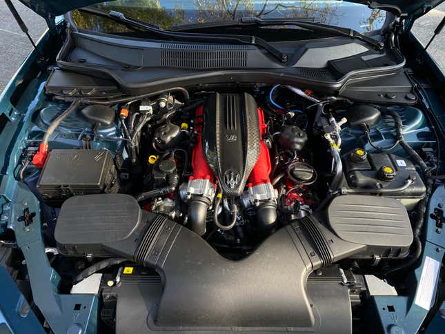 An under-hood shot showing the beautiful Maserati V8 painted red with a carbon fiber engine cover