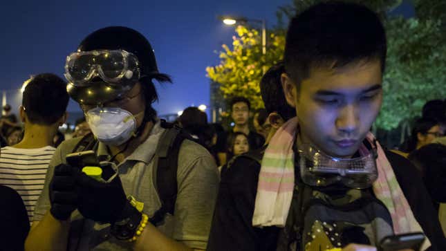 Protesters look their phones as they block the entrance to the offices of Hong Kong's Chief Executive Leung Chun-ying in Hong Kong October 2, 2014. Hong Kong authorities on Thursday urged thousands of pro-democracy protesters to immediately end their blockade of the city centre and said any attempt to occupy administrative buildings would be met with a resolute and firm response. REUTERS/Tyrone Siu