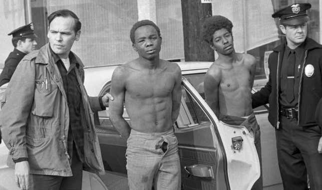 Police officers hold two members of the Black Panthers that were arrested after police laid siege to the party headquarters. Three police officers were shot when they attempted to enter the building with warrants searching for guns