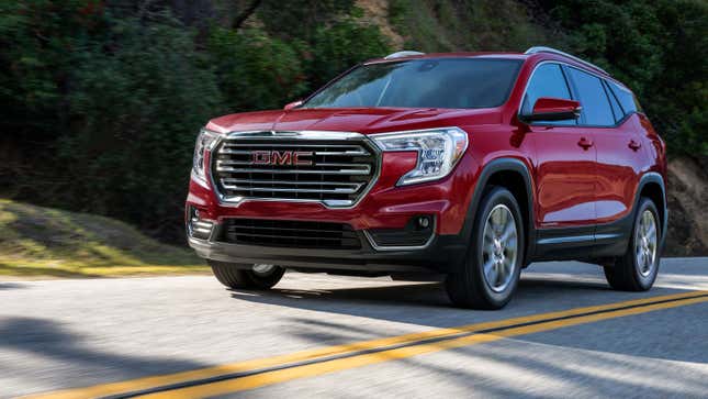 Un GMC Terrain rouge roulant devant une colline verte