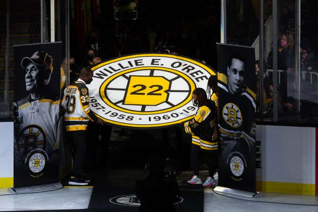 Anson Carter helps carry the banner as former Boston Bruins player Willie O’Ree has his No. 22 jersey retired prior to the game between the Carolina Hurricanes and the Boston Bruins at the TD Garden on January 18, 2022 in Boston, Massachusetts.